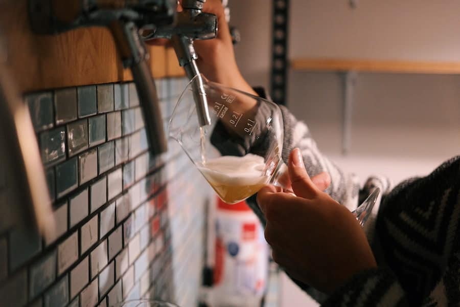 A person refilling beer in a glass