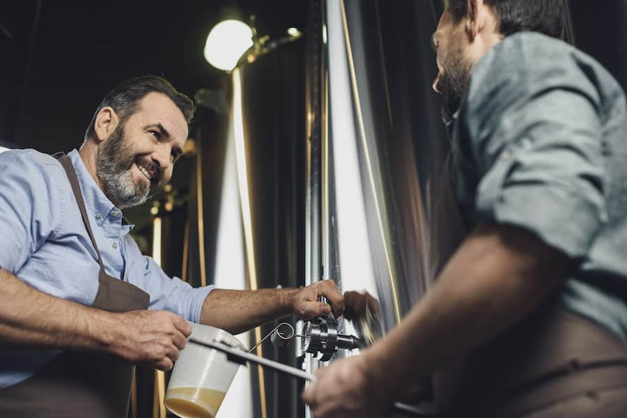 Two men checking beer after fermentation