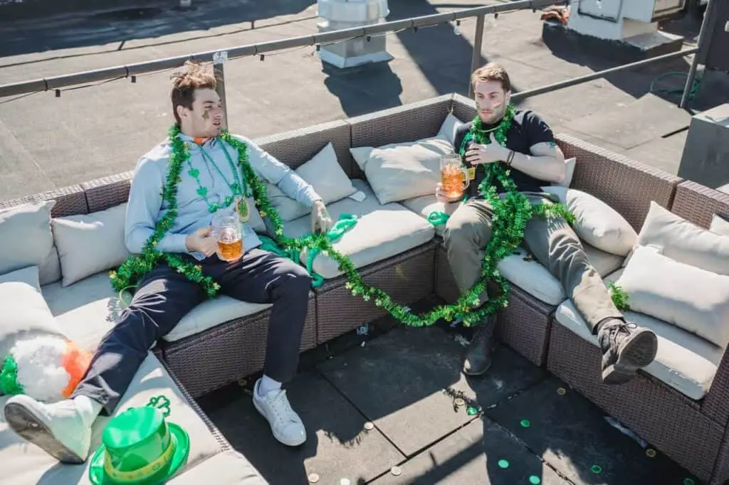 An image of two friends drinking on a couch