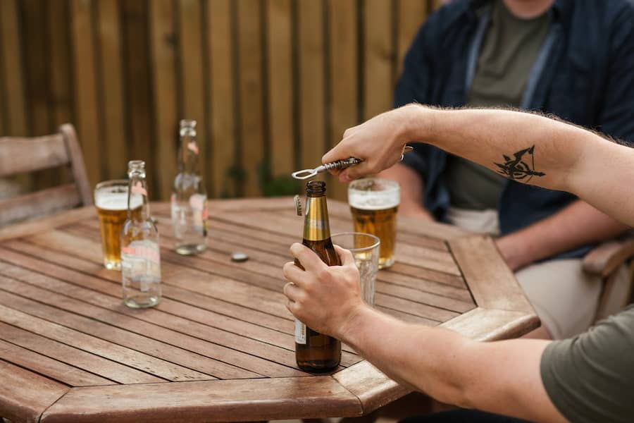 A person opening a bottle of beer using a bottle opener