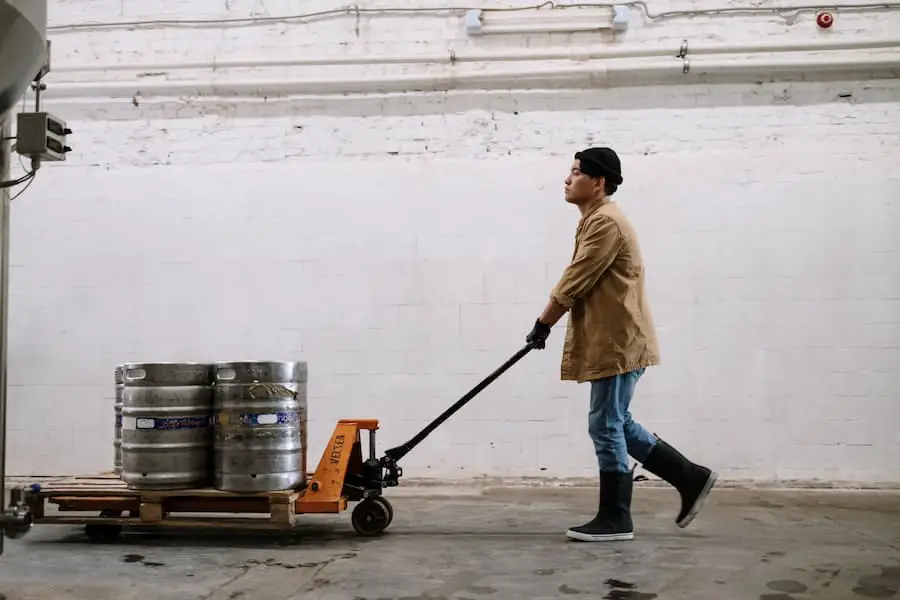 A man pushing a cart with thumper kegs