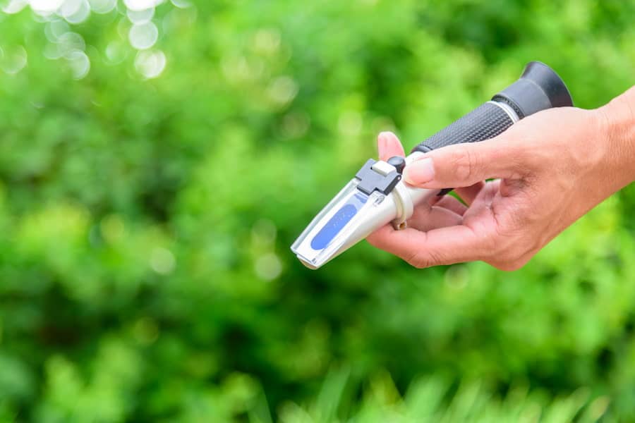 An image of a person's hand holding a refractometer