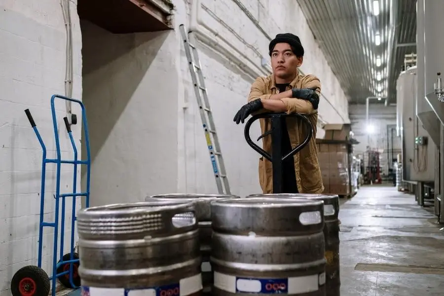 An image of a man standing in front of kegs
