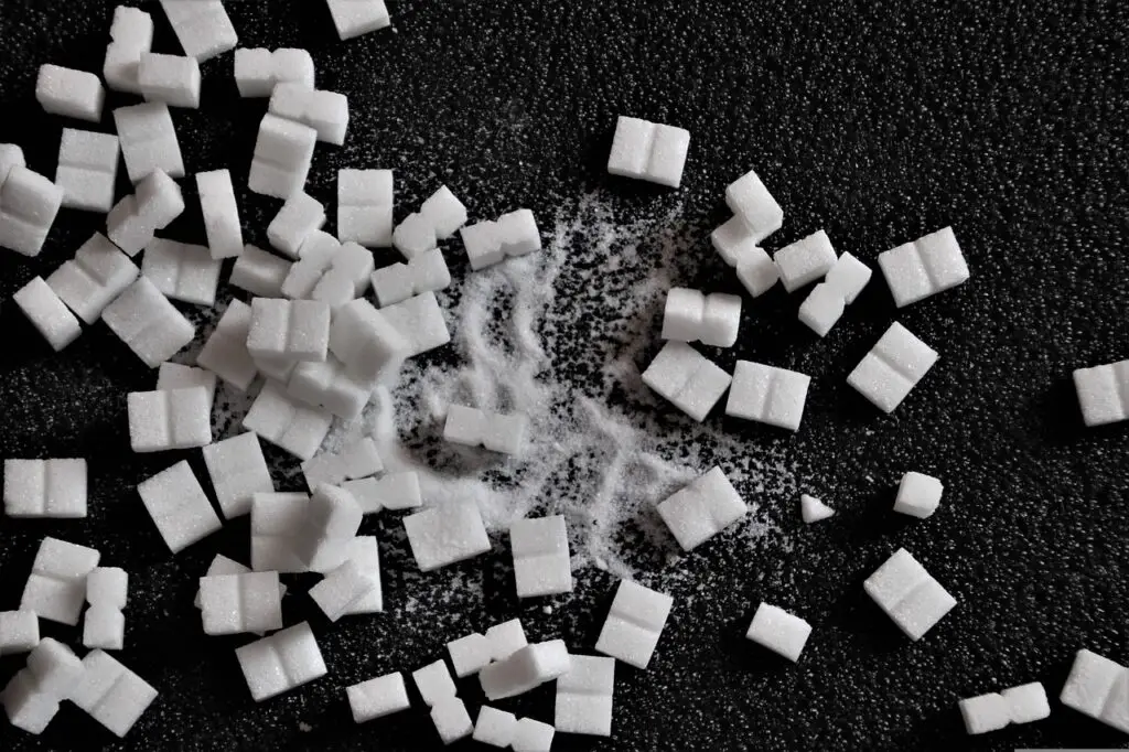 Cubes and powdered white sugar are scattered on a black surface in the kitchen