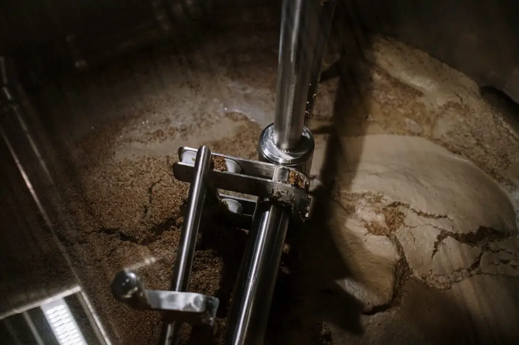 A stainless steel machine fermenting a fresh batch of beer in a dim-lit brewery