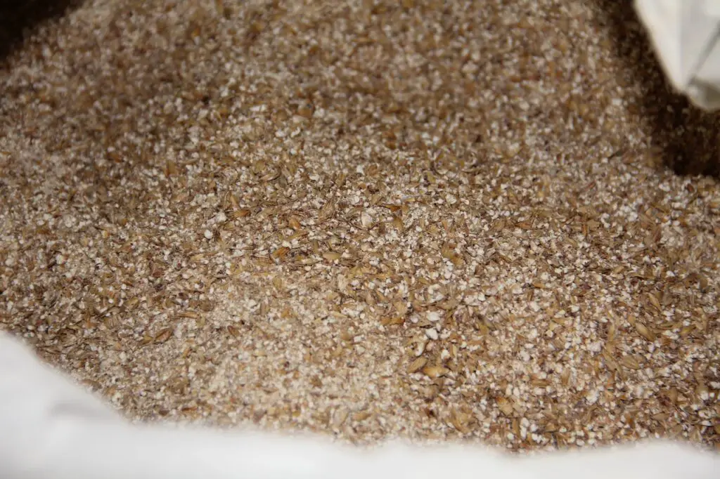 Crushed grains of barley malt for brewing craft beer are placed on a white sack