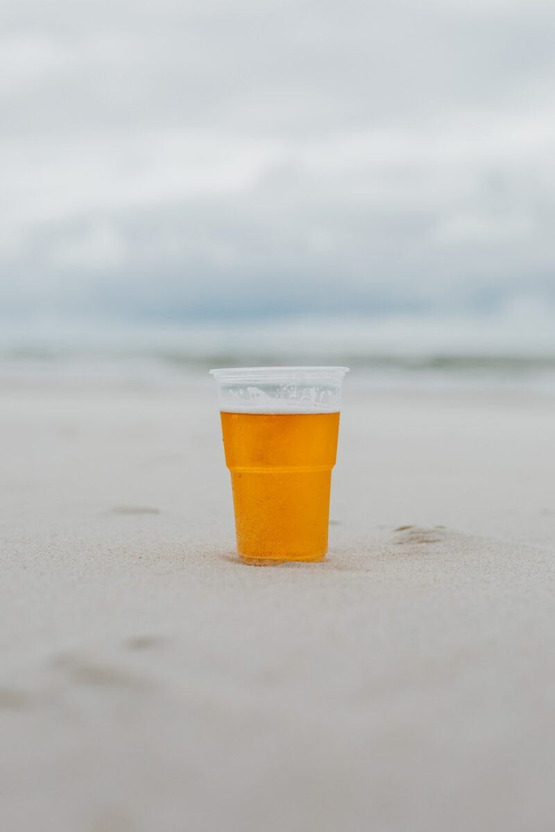 A glass of cold beer was placed on the sand on the beach
