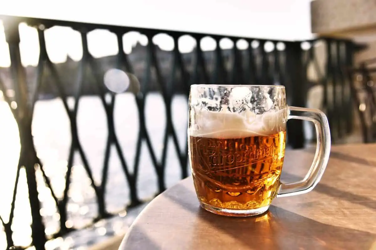 A clear mug with half-filled foamy beer was placed on top of a wooden table