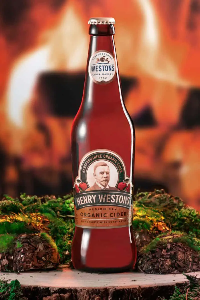A bottle of Henry Westons organic cider was placed on top of a wooden surface